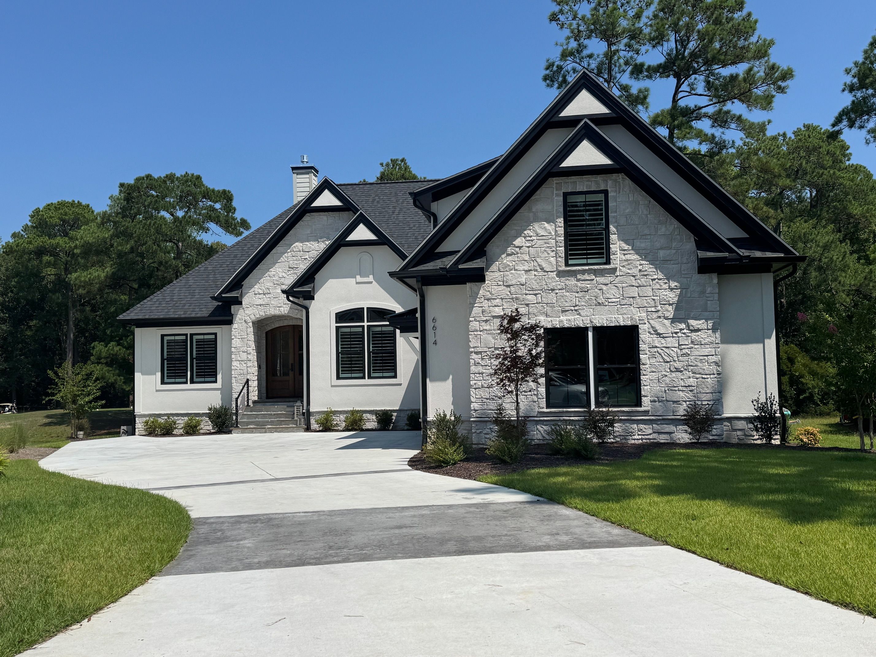Stone, steep gables and black-framed windows on a private wooded lot.